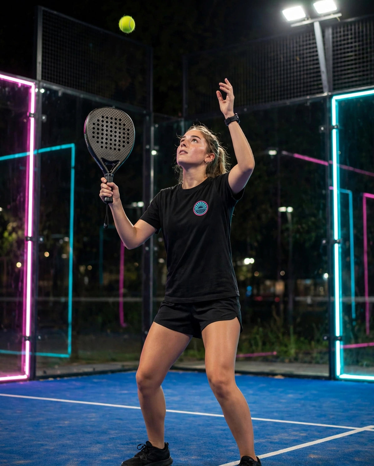 Model wearing the After Hours Chest Logo Tee in black on a padel court at night